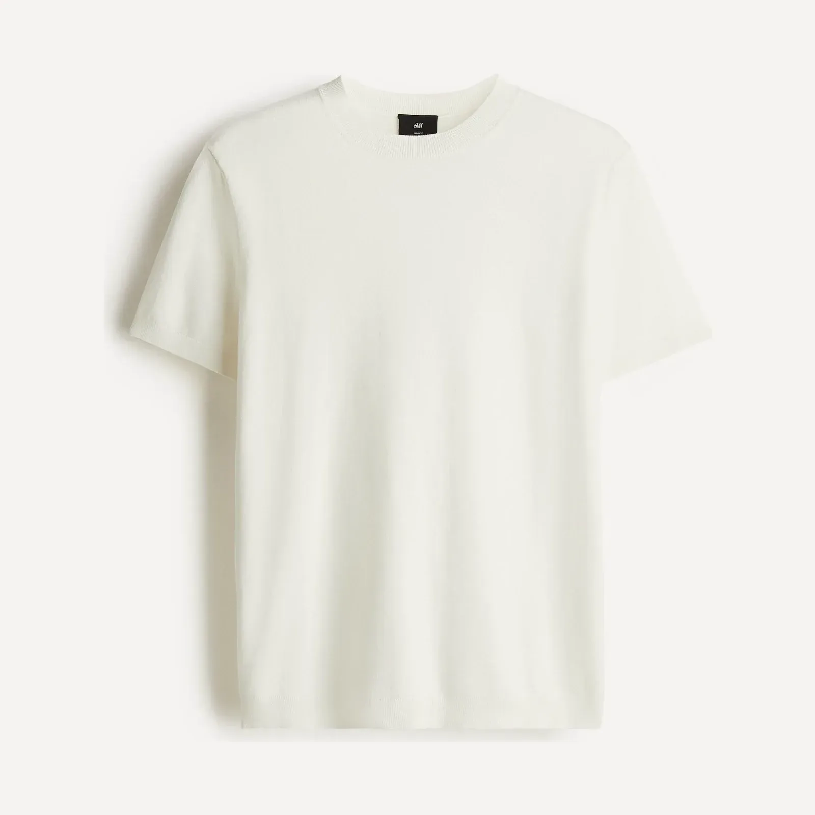 Off-white t-shirt H&M z krótkim rękawem, z drobnej dzianiny, z okrągłym, prążkowanym dekoltem, ujęcie produktowe.